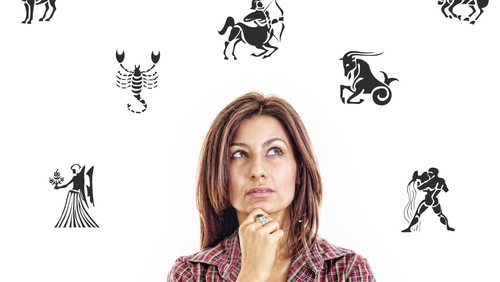 woman surrounded with zodiac signs thoughtfully looking up with