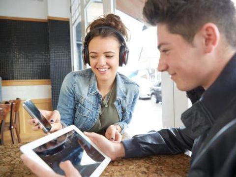 Late teens boy and girl using technology in a cafe