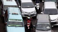 Pemotor terjebak di antara mobil.