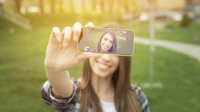 Beautiful young woman taking a selfie with phone