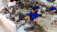 Tiga orang narapidana sedang menyelesaikan memodifikasi motor.