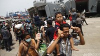 Mantan anggota Gafatar turun dari kapal sambil membawa anak dan istrinya.