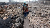 Seorang ibu sambil menggendong anaknya melintas di lokasi kebakaran.