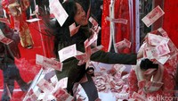 Seorang pengunjung wanita berebut uang yang berhamburan didalam kotak kaca karena tiupan blower.  Istimewa/Reuters/Stringer.