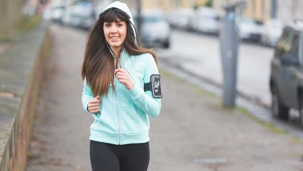 Beautiful young woman jogging alone on city  street