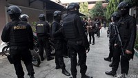 Polisi bersenjata lengkap berjaga di depan kos saat petugas lainnya melakukan razia.