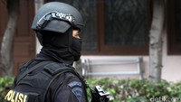 Polisi bersenjata lengkap berjaga di depan kos.
