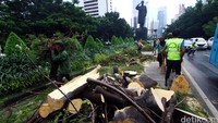 Petugas polisi tampak membantu mengamankan lalu lintas kendaraan saat pembersihan pohon tumbang tersebut.