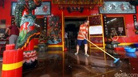 Seorang pekerja membersihkan lantai vihara.