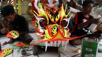 Dua orang pengrajin menyelesaikan pembuatan kepala liong.