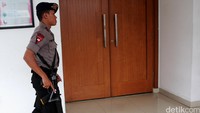 Polisi bersenjata laras panjang berjaga di pintu masuk ruang sidang. 