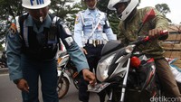 Petugas Polisi Militer melepas sebuah stiker yang menempel di motor salah seorang pengandara.