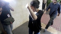 Sendy tampak menutupi wajahnya dari sorotan kamera wartawan.