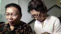 Imelda mengenakan kemeja berwarna krem dibalut celana panjang motif bunga-bunga warna biru.
