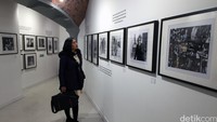 Seorang pengunjung sedang memperhatikan koleksi foto John Lennon.