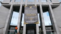 Petugas kebersihan bekerja di bawah spanduk pendaftaran hakim agung.
