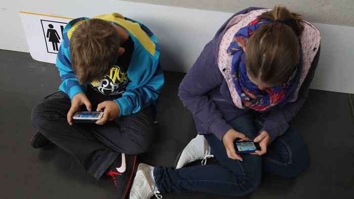 RUESSELSHEIM, GERMANY - SEPTEMBER 22:  Children play video games on smartphones while attending a public event on September 22, 2012 in Ruesselsheim, Germany. Smartphones, with their access to social networks, high-resolution screens, video games and internet acess, have become commonplace among children and teenagers across the globe.  (Photo by Sean Gallup/Getty Images)