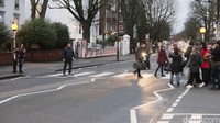 Sejumlah turis bergerombol di sisi kanan jalan untuk merekam momen rekan mereka yang melintas.