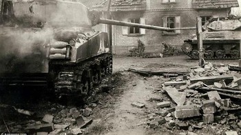 Tank yang rusak dengan latar belakang paramedis merawat tentara yang terluka. Foto: Argunners.com