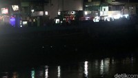 Di pinggir sungai ada jalan inspeksi. Rumah permanen dan tempat hiburan malam nampak berpendar di temaram. Lampu-lampunya memang menampakkan iklan minuman beralkohol.