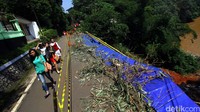 Warga melintas disamping jalan yang longsor di Jalan Gardu, Srengseng Sawah, Jagakarsa, Jakarta Selatan, Minggu (14/2/2016). 