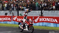 Berdiri diatas motornya yang sedang melaju, Dani Pedrosa melambaikan tangan ke arah para penonton. 