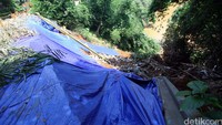 Tampak terpal berwarna biru menutupi kawasan longsor tersebut.
