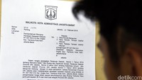 Seorang warga sedang membaca surat peringatan (SP) 1 dari Pemkot Jakarta Barat terkait relokasi kawasan tersebut.
