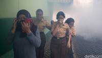 Siswa dan guru menutup hidung mereka untuk menghindari asap fogging.