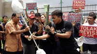 Demonstran menyerahkan replika korek kuping raksasa kepada anggota DPR Fraksi Gerindra Martin Hutabarat.