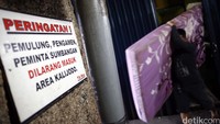 Seorang penghuni menggotong kasur meninggalkan kawasan Kalijodo.