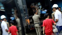 Satpol PP membantu warga mengevakuasi barang-barangnya.