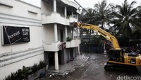 Eskavator menggempur dinding kafe milik Daeng Aziz.