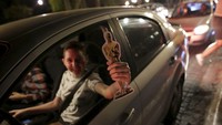 Seorang pria menunjukan gambar dari piala Oscar sambil tersenyum bahagia. REUTERS/Daniel Becerril/detikFoto.