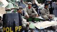 Satpol PP beristirahat di atas puing-puing bangunan.