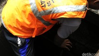 Petugas nyemplung ke gorong-gorong untuk mengambil bungkus kabel yang menyumbat saluran air.