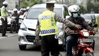 Polisi memberhentikan pengendara sepeda motor untuk diperiksa kelengkapan suratnya.