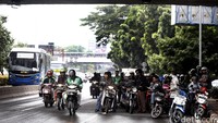 Pengendara sepeda motor berteduh di kolong jembatan Senayan.