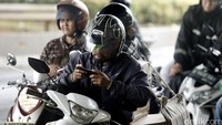 Beberapa di antara pemotor menunggu hujan reda dengan bermain handphone.