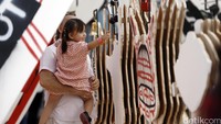 Seorang pengunjung asing mengajarkan anaknya tentang alat musik tradisional yang dipajang di arena Instalasi Seni MLDSpot Art&Sound Experience.