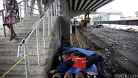 Seorang pekerja tertidur setelah lelah membongkar badan jembatan.