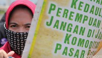Seorang wanita membawa poster dalam demonstrasi di depan Istana Merdeka.