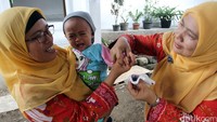 Sambil menangis seorang anak yang telah diberikan vaksin polio ditandai tangannya.