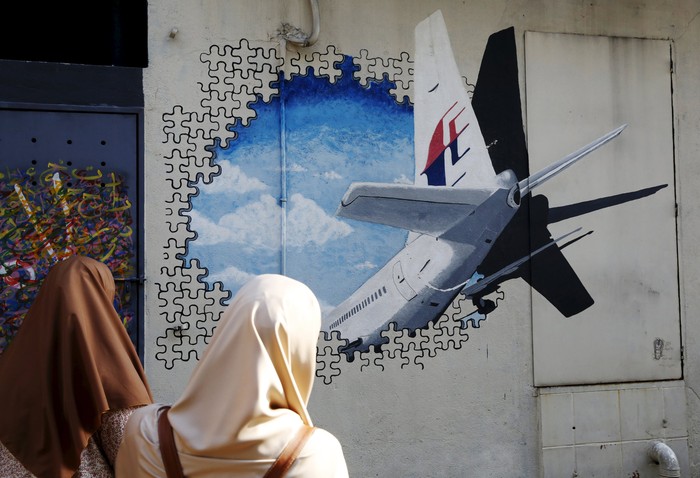 Women look at a mural of missing Malaysia Airlines flight MH370 two years after it disappeared, in Kuala Lumpur, Malaysia, March 7, 2016. REUTERS/Olivia Harris        EDITORIAL USE ONLY. NO RESALES. NO ARCHIVE