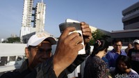 Seorang laki-laki mengabadikan peristiwa gerhana dengan  handphone yang dilapisi negatif film.