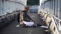 Seorang warga asing melakukan salat gerhana beralaskan koran di atas JPO.