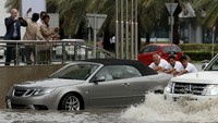 Sejumlah orang abadikan, orang-orang yang mendorong mobil untuk lalui banjir. Ahmed Jadallah/Reuters.