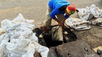 Petugas mengangkat lumpur dari dalam gorong-gorong. Bisma Alief/detikcom.