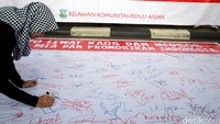 Seorang warga menandatangani spanduk dukungan terhadap program ini.