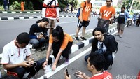 Relawan mengambil sampah di samping warga yang tampak acuh.